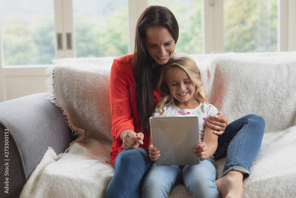 Mother and daughter using digital tablet in living room Mother and daughter using digital tablet in living room