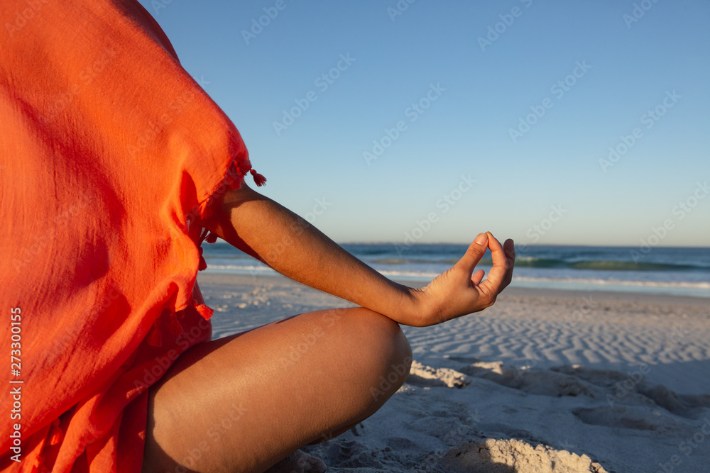 Woman doing yoga on beach in the sunshine