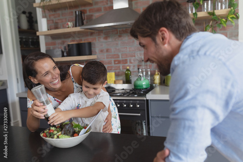 Family preparing vegetable salad in kitchen at home