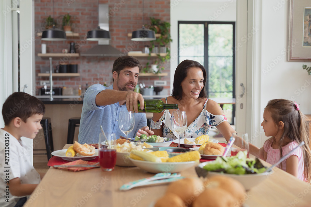 Family having food and champagne on dining table at home