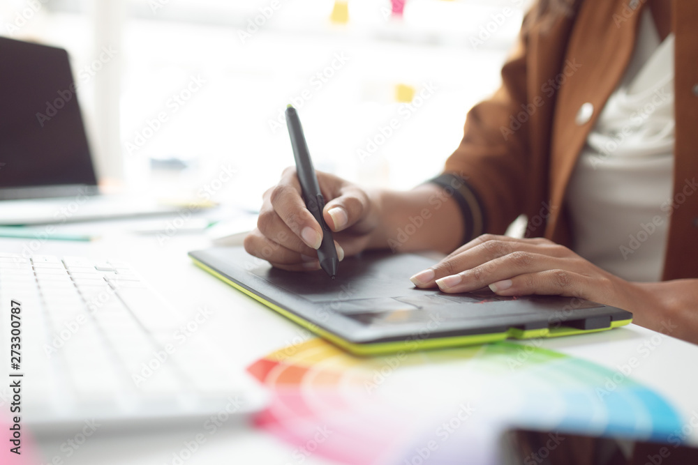 Female graphic designer using graphic tablet at desk in a modern office Female graphic designer using graphic tablet at desk in a modern office