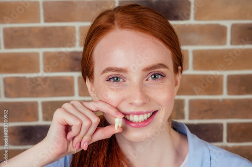 Canvas Print redhaired ginger female with snow-white smile holding white wisdom tooth after s