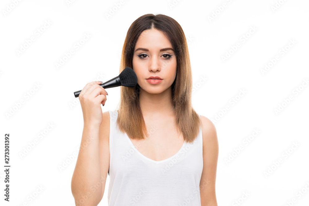 Young woman over isolated white background with makeup brush Young woman over isolated white background with makeup brush