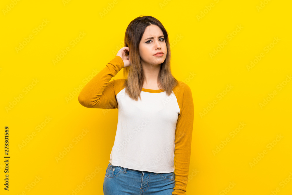 Pretty young woman over isolated yellow wall having doubts Pretty young woman over isolated yellow wall having doubts