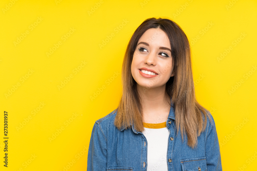 Young woman over yellow background laughing and looking up Young woman over yellow background laughing and looking up