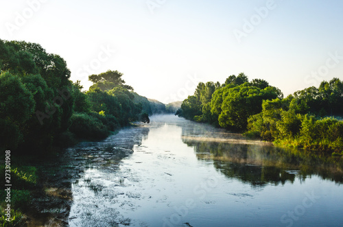 Mist over the river at dawn. River flowing through the forest in the early morning