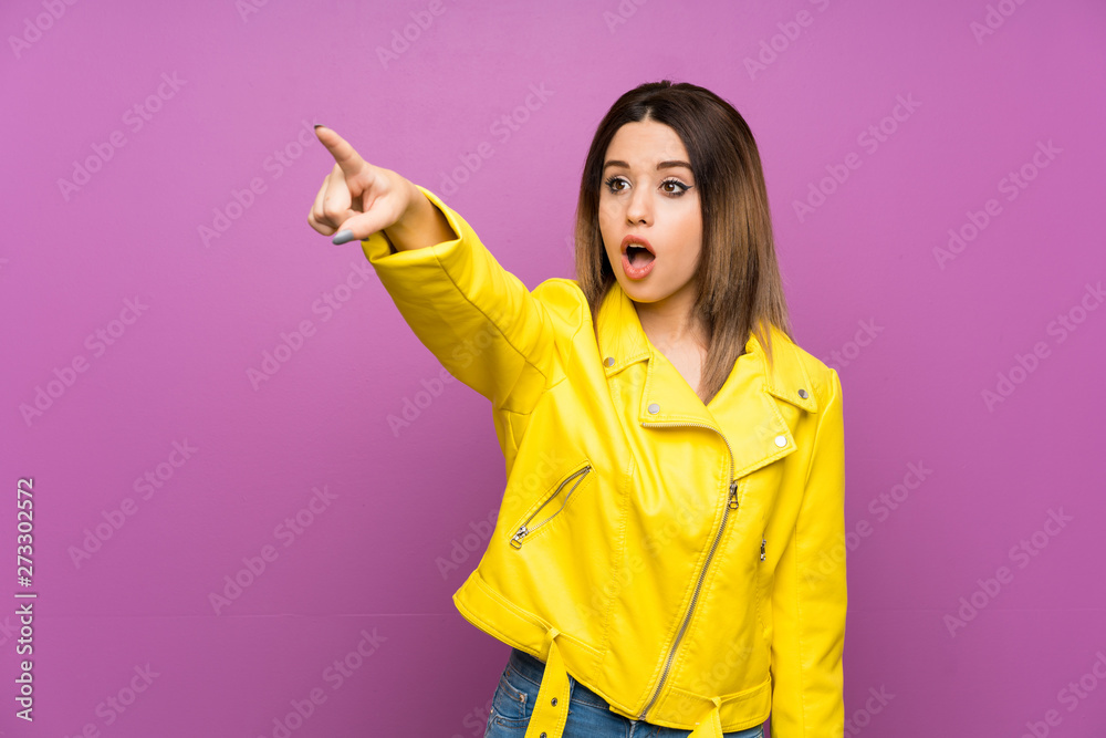 Young woman over purple background pointing away Young woman over purple background pointing away
