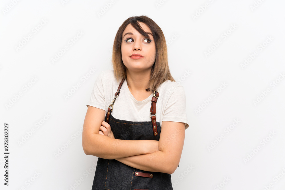Young woman with an apron making doubts gesture while lifting the shoulders Young woman with an apron making doubts gesture while lifting the shoulders