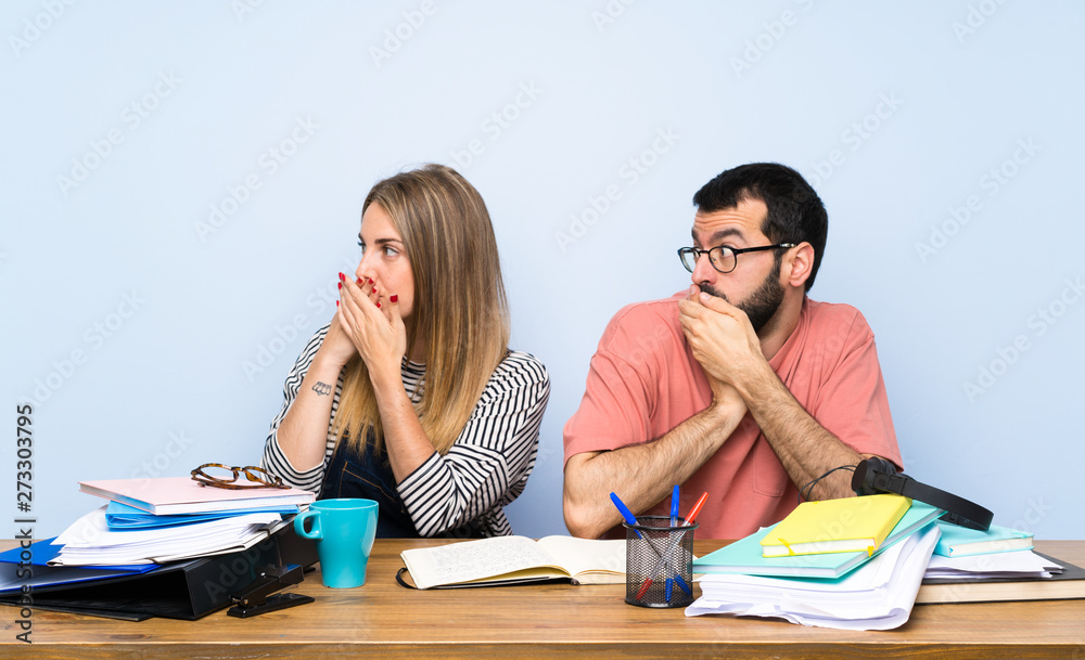 Students with many books covering mouth and looking to the side Students with many books covering mouth and looking to the side