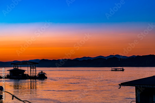 Fototapeta Naklejka Na Ścianę i Meble -  Beautiful Silhouette Orange Sunset on the Lake Hill with Many Birds Flying.