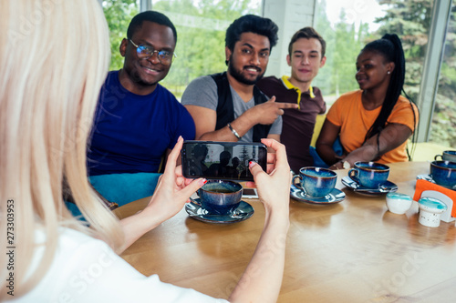 Canvas Print multinational group of happy friends enjoy and drinking tea and taking photos selfie on photocamera in cafe
