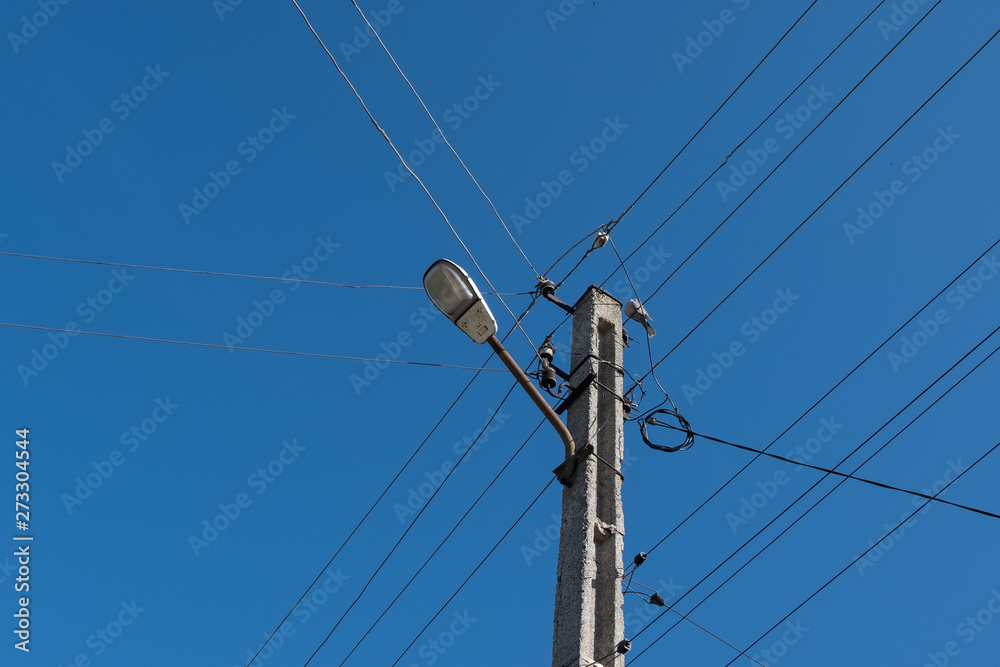 Street lamppost with wires. Concrete pole with a lantern. Street lamp with a bird. Street lamppost with wires. Concrete pole with a lantern. Street lamp with a bird.