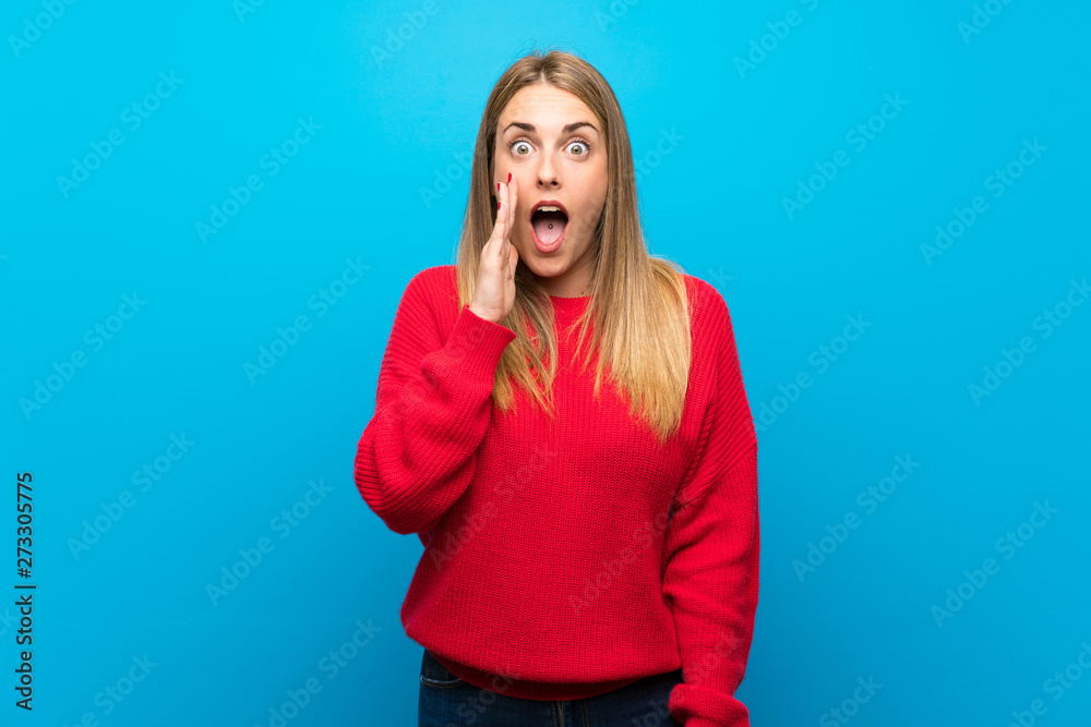 Woman with red sweater over blue wall with surprise and shocked facial expression Woman with red sweater over blue wall with surprise and shocked facial expression