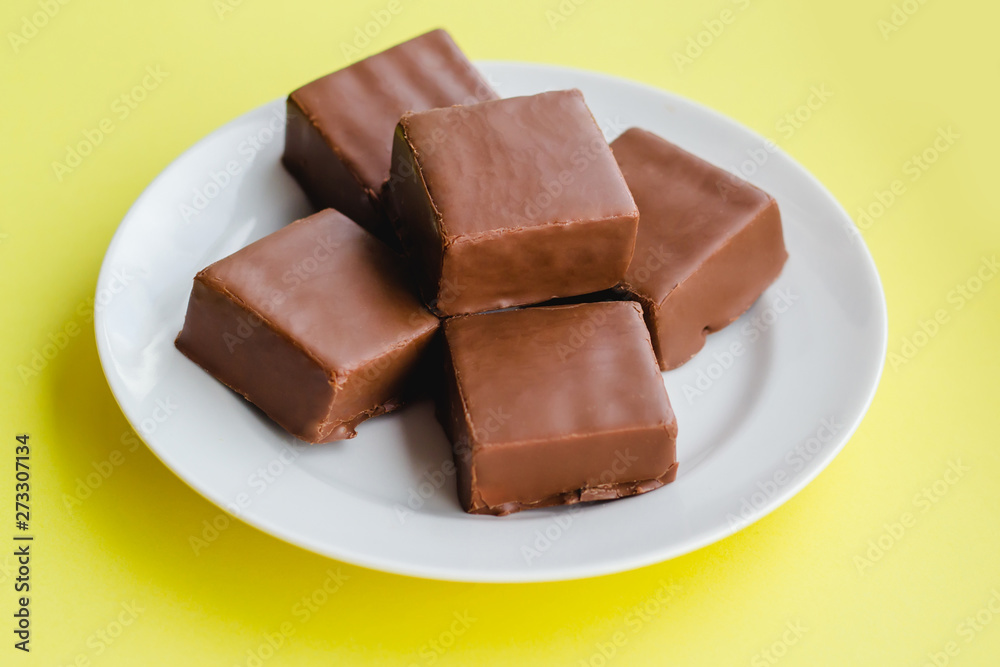 Chocolate sweets on a plate on a yellow background. Chocolate sweets on a plate on a yellow background.