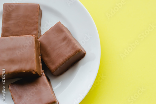 Chocolate sweets on a plate on a yellow background.