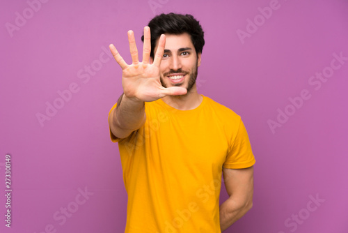 Obraz na plátně Handsome over isolated purple wall counting five with fingers