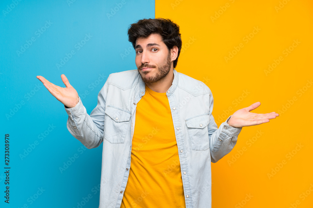 Handsome over isolated colorful background making doubts gesture Handsome over isolated colorful background making doubts gesture