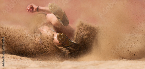 Female athlete long jump landing sand spray