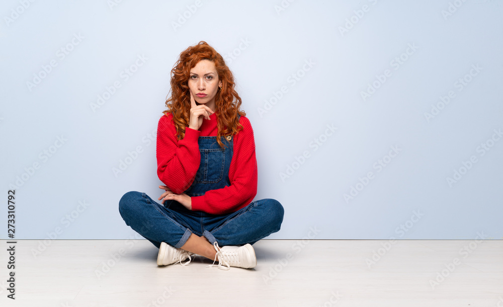 Redhead woman with overalls sitting on the floor Looking front Redhead woman with overalls sitting on the floor Looking front