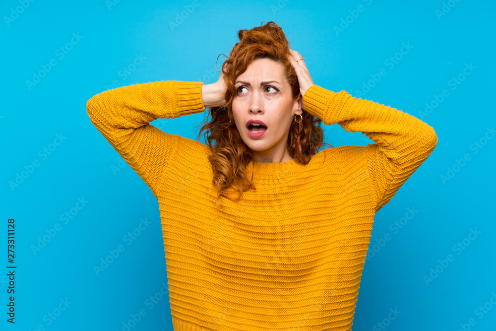Redhead woman with yellow sweater frustrated and takes hands on head Redhead woman with yellow sweater frustrated and takes hands on head