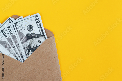 Paper envelope with money on a yellow background.