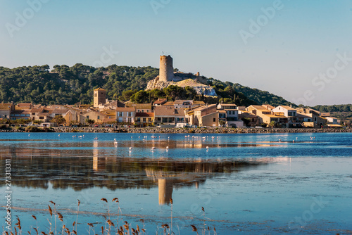 Historical center of Gruissan town with Barberousse Tower in top seen from the opposite side of the pond. Occitanie, France.