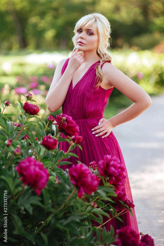 Outdoor close up portrait of beautiful young woman with long blonde hair, makeup, posing in the blooming garden. Female spring fashion concept Outdoor close up portrait of beautiful young woman with long blonde hair, makeup, posing in the blooming garden. Female spring fashion concept