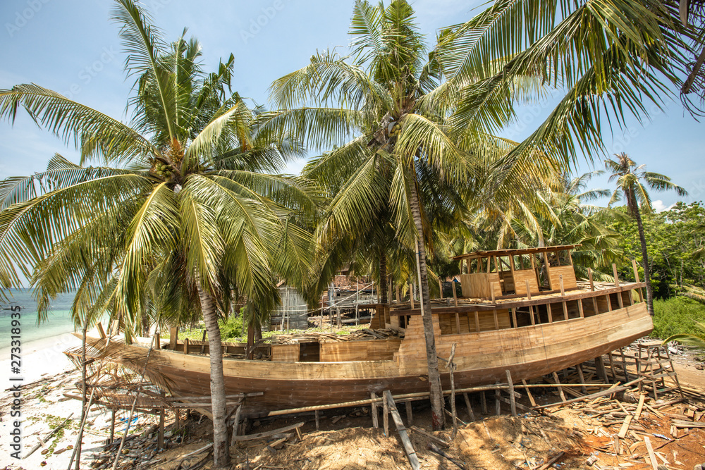 Obraz premium Wooden big boat building between Palms at the Beach