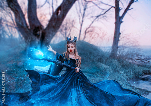 Photos strict witch with magical magical glowing and sparkling staff in her hands, lady