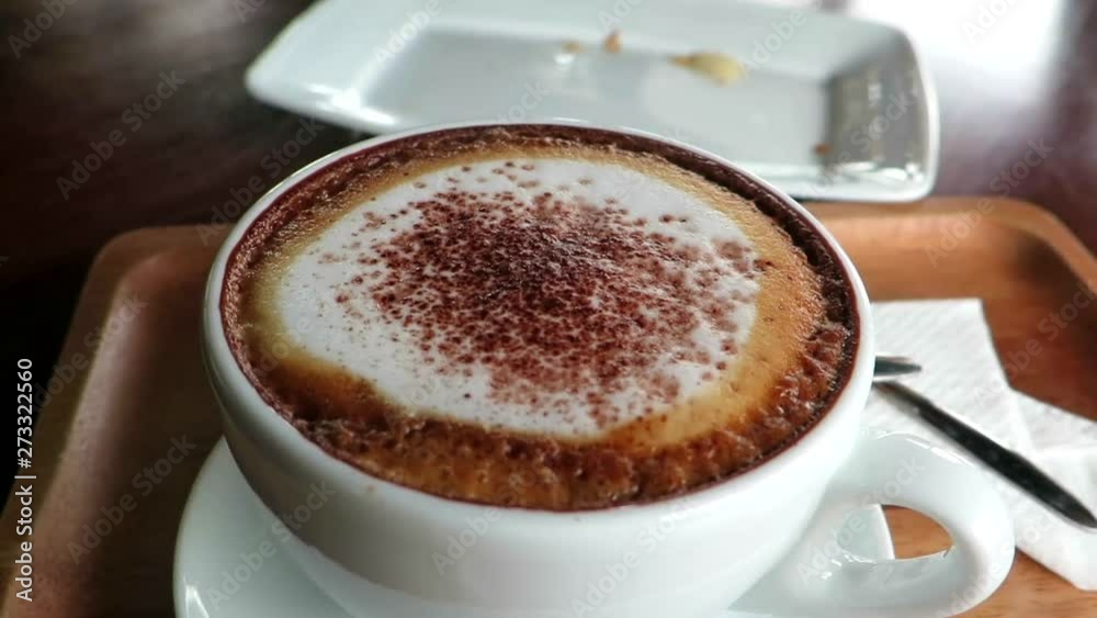 Almond croissant diving into creamy foam over Italian style cappuccino Almond croissant diving into creamy foam over Italian style cappuccino
