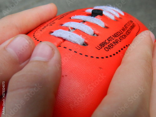 Two hands holding a red football