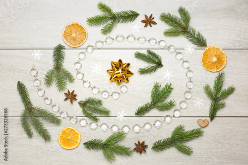 Christmas spiral decoration with dried oranges, aniseed stars, fir tree branches and glass bead chain on white wooden background photo