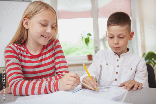 Childhood, leisure concept. Adorable kids drawing together during art class. Happy healthy kids develop creativity at school photo