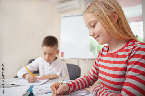 Cropped shot of a girl and boy looking concentrated, drawing together at school. Children enjoying learning to draw at elementary school, copy space © Ihor