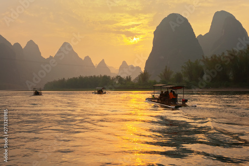 Tourists ride along the Li River (Lijiang River) on traditional bamboo rafts and admire the beautiful sunset. Xingping. China