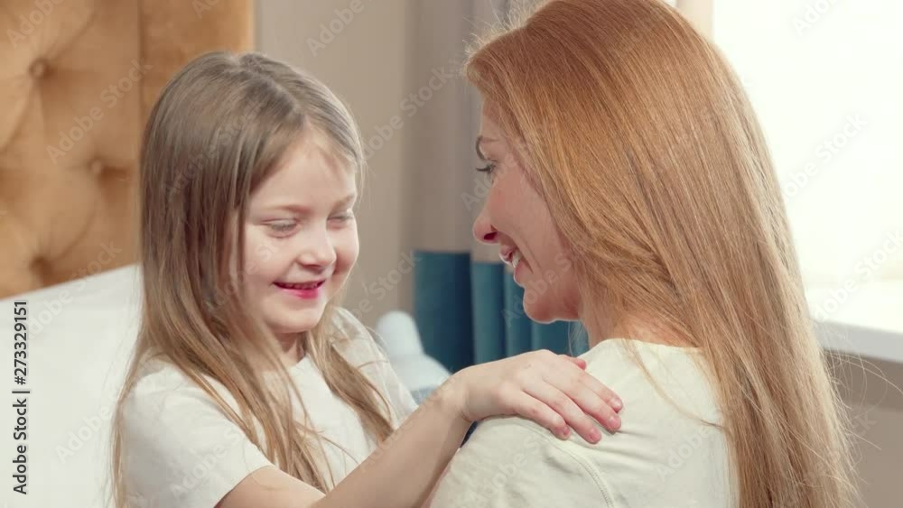 Cute little girl hugging her mother with her eyes closed. Loving mother embracing her little daughter. Mom and child hugging at home. Love, affection, family concept Cute little girl hugging her mother with her eyes closed. Loving mother embracing her little daughter. Mom and child hugging at home. Love, affection, family concept