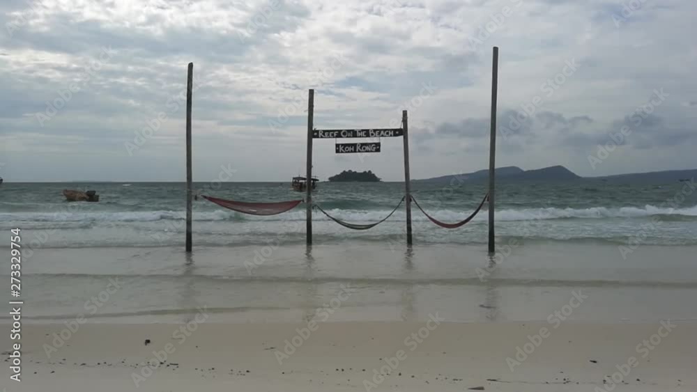 Hammocks hanging on wooden poles into the sea and swinging Hammocks hanging on wooden poles into the sea and swinging