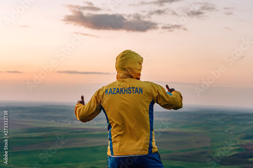 The guy in the yellow jacket stands on mount Kazygurt. Orange sunset in the sky. Nature in Turkestan region of Kazakhstan. photo