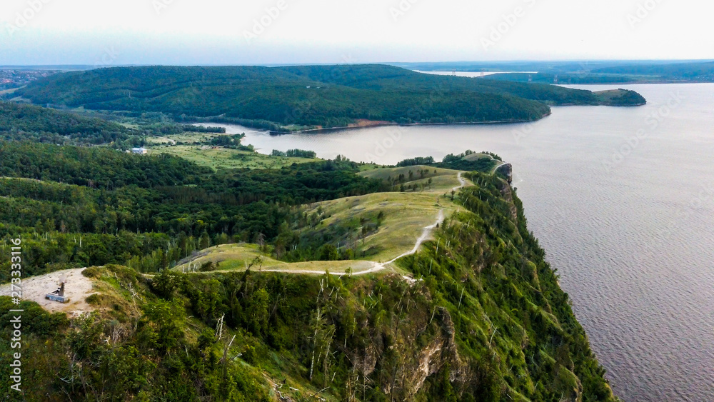 Obraz premium Arial view of Zhiguli mountains with green trees and Volga river in Samarskaya Luka national park during summer evening, Samara region, Russia