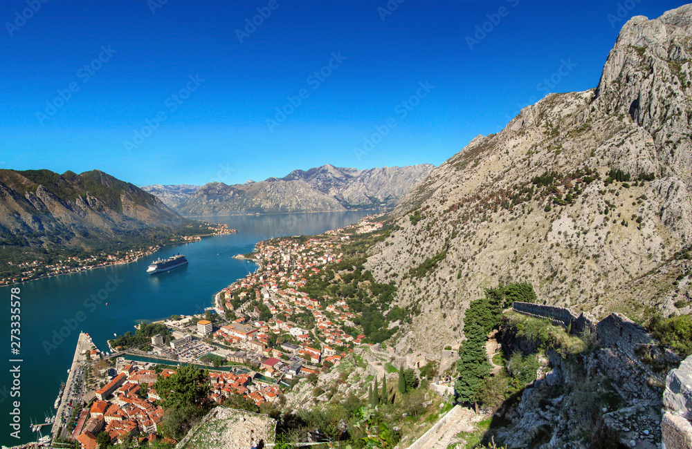 Landscape of Kotor bay, Montenegro, Europe. Beautiful view with the sea, mountains, old city, cruise ship, harbor, green trees and blue sky in a sunny summer day. 