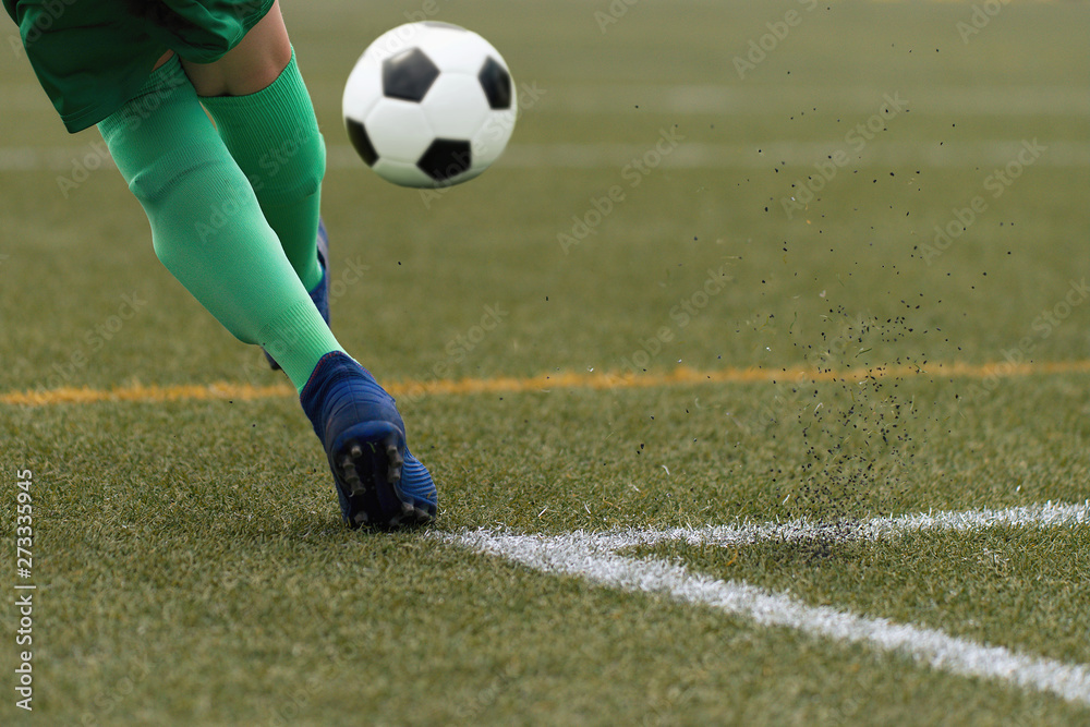 Foot of a child football player and ball on the football field Foot of a child football player and ball on the football field