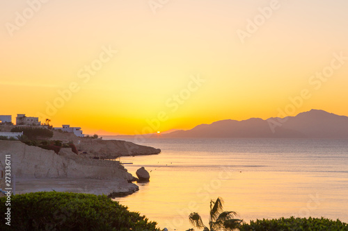 Sunrise over the red sea. Beautiful bright sky with sun rays and morning clouds. Sea and boats. View of Tiran Island. Egypt, Sharm El Sheikh. Tourism and travel.