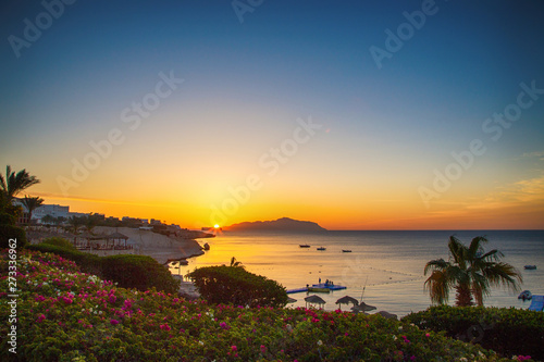 Sunrise over the red sea. Beautiful bright sky with sun rays and morning clouds. Sea and boats. View of Tiran Island. Egypt, Sharm El Sheikh. Tourism and travel.