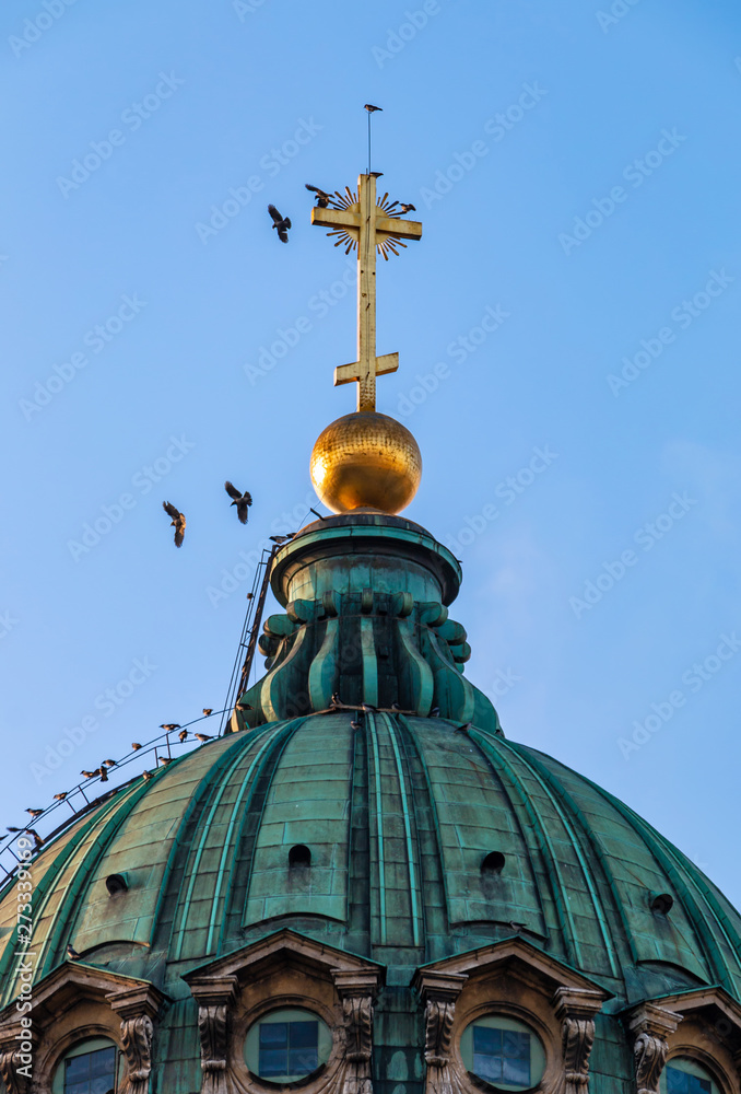 Kazan cathedral located in Saint-Petersburg, Russia. Orthodox church dome with golden cross and birds against the blue sky