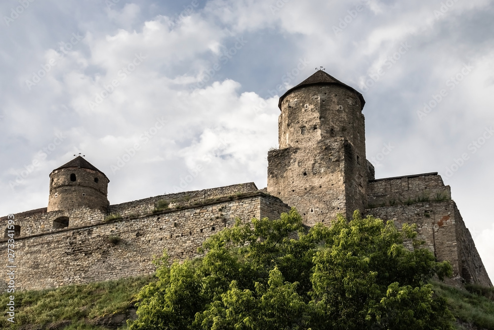 Two towers and stone walls of the medieval Kamianets-Podilskyi fortress of the XVI century on a hill on the background of a blue sky. Ukraine.