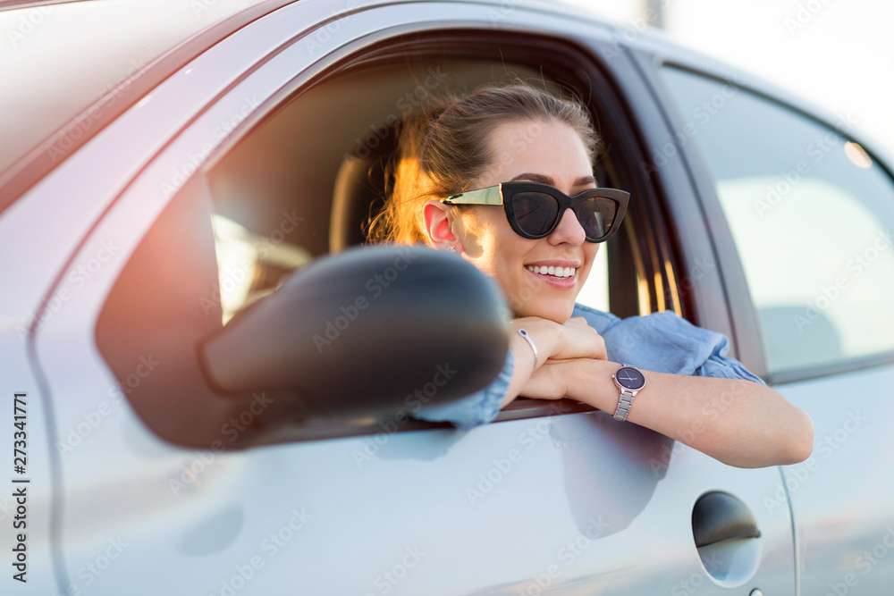 Naklejka premium Happy woman driving a car and smiling