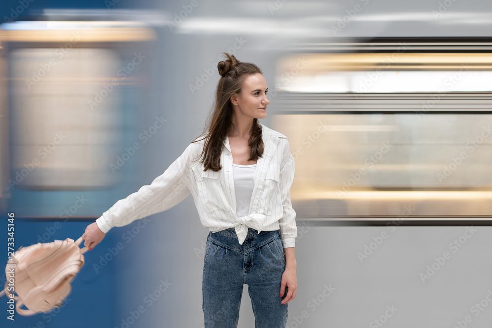 The girl swings a backpack against the background of a passing train. The train and backpack are shown in motion to convey a dynamic atmosphere. This is the author's idea.