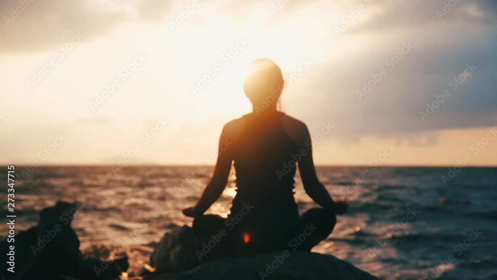 Young woman in bodysuit practicing yoga on the beach above sea at amazing sunrise. Young woman in bodysuit practicing yoga on the beach above sea at amazing sunrise.