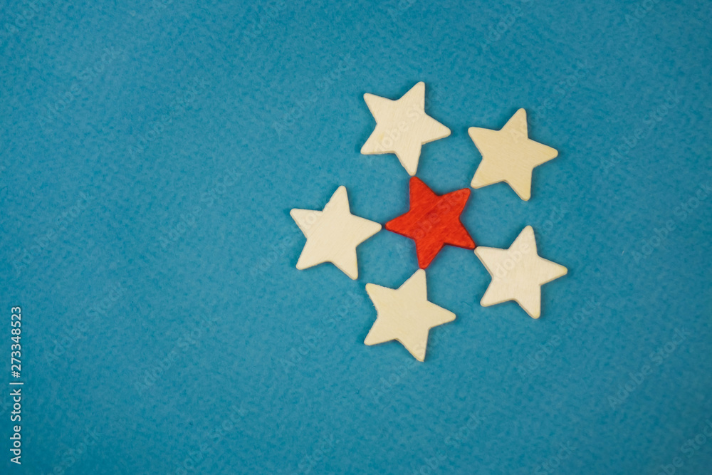 a bunch of wooden stars and one of them is highlighted in red. subject on blue background a bunch of wooden stars and one of them is highlighted in red. subject on blue background
