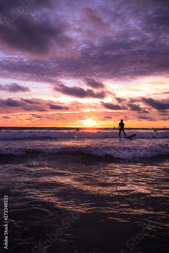 Surfers having fun on sunset time in Bali